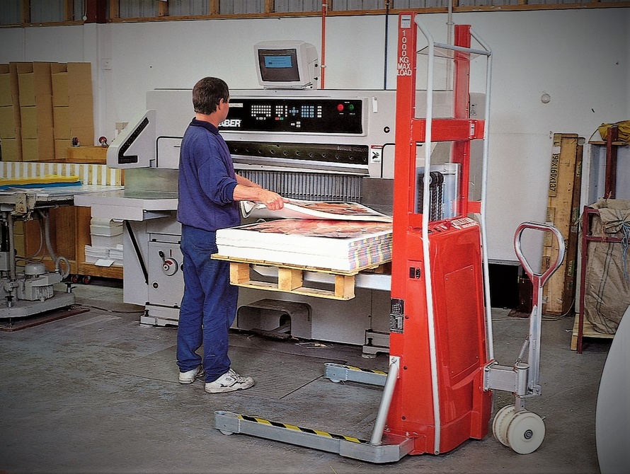 Man using a Quikstak® pallet stacker by a guillotine